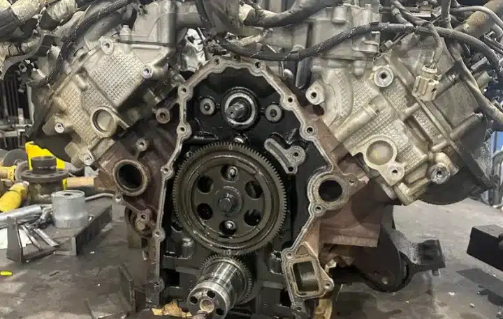 Engine Repair & Replacement In Monticello AR At Strokers Diesel Performance & Repair. A close-up view of a partially disassembled V-shaped engine, revealing internal gears and components with various wires and mechanical parts visible around it.